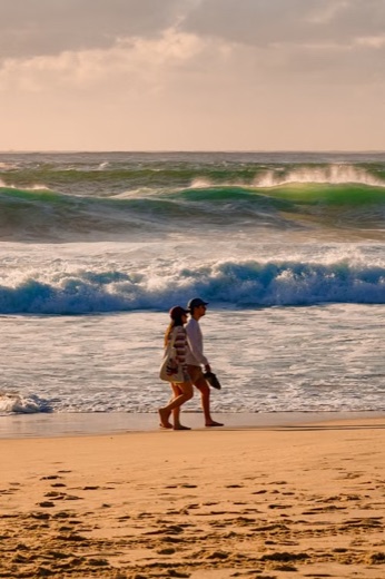 Couple walking along a beach at sunset