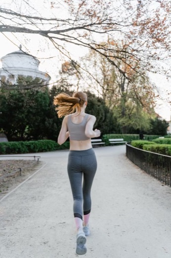Woman running on a tree-lined park path