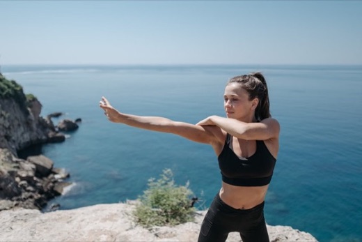 Woman stretching on a cliff overlooking the ocean